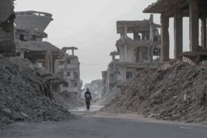 Lone figure walks through the rubble of war in the Middle East