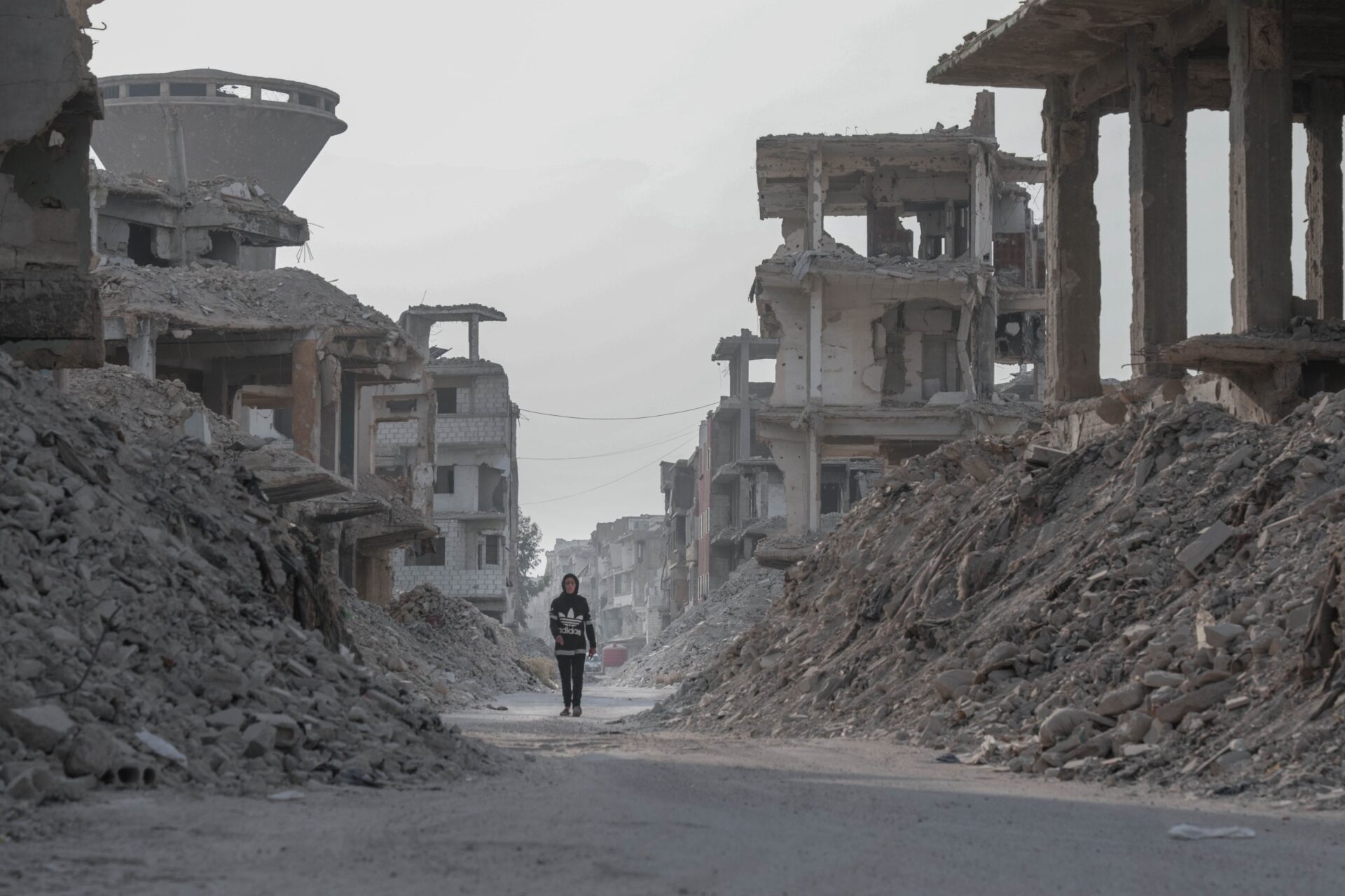Lone figure walks through the rubble of war in the Middle East
