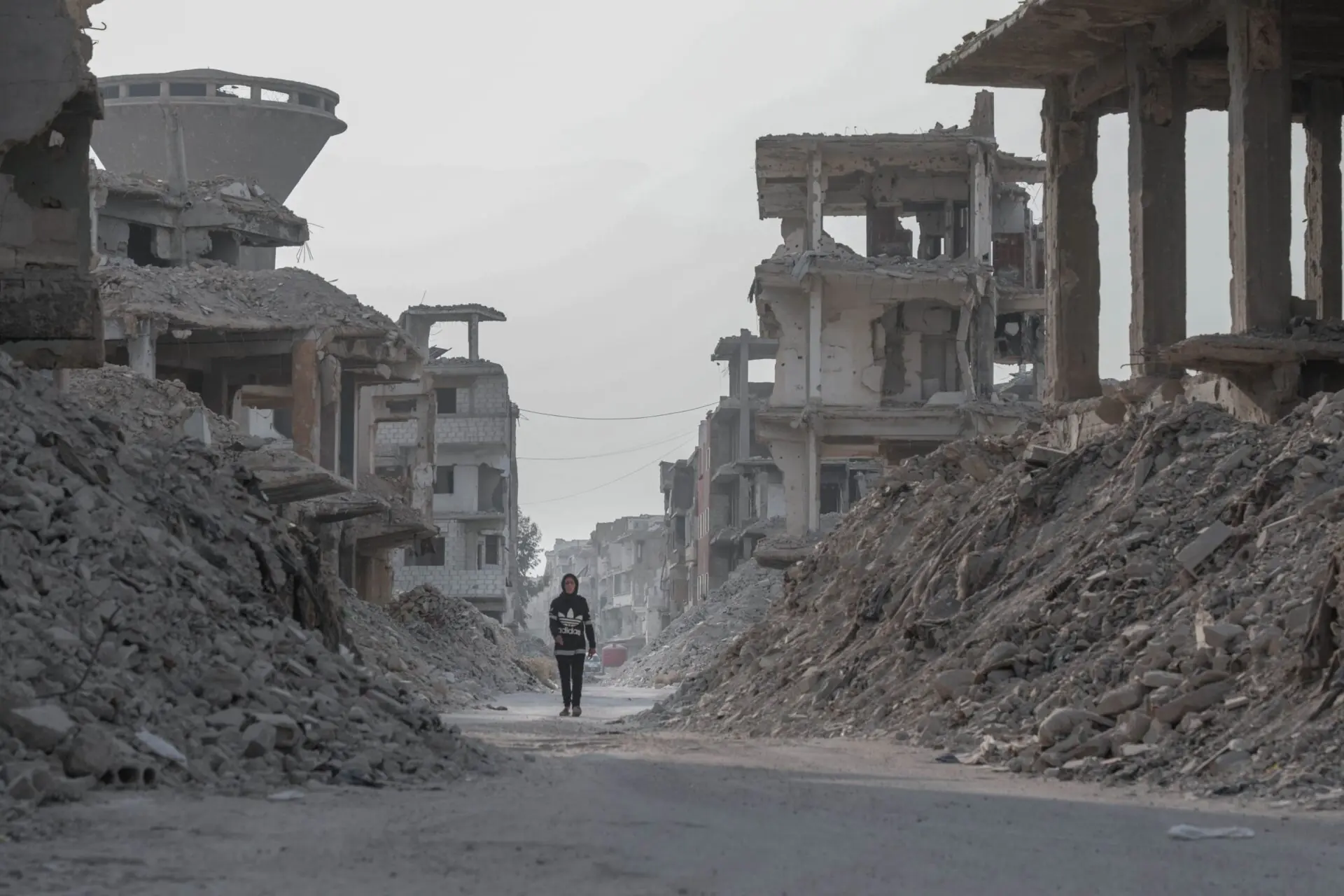 Lone figure walks through the rubble of war in the Middle East